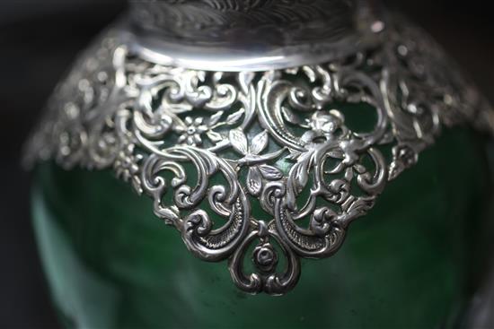A late Victorian pierced repousse silver mounted green and clear cut glass claret jug by William Comyns, London, 1897, 26cm.